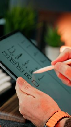 Hand using a stylus on a tablet with a checklist on screen
