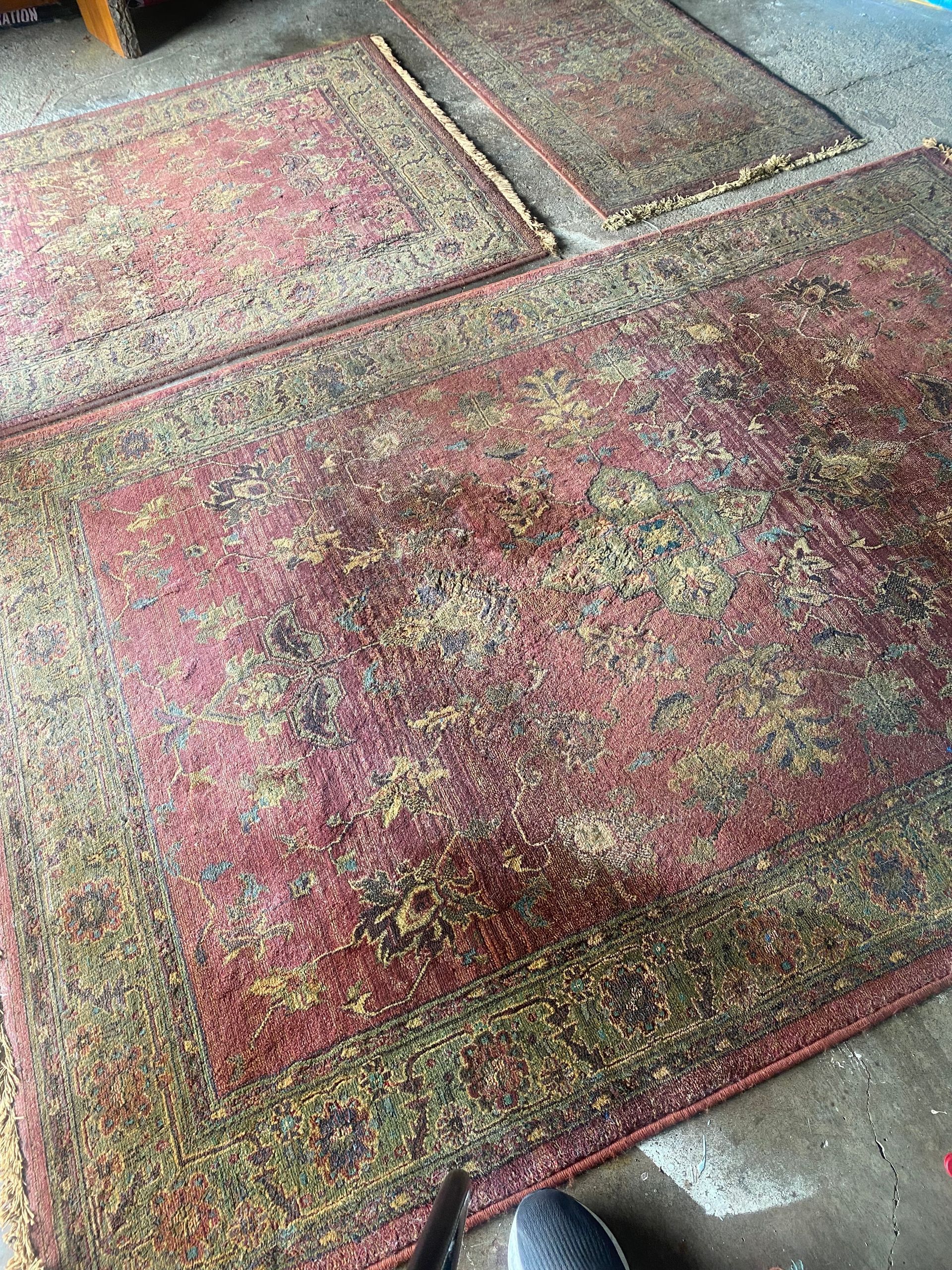 Patterned red and pink rug on a gray floor, with a second rug partially visible nearby.
