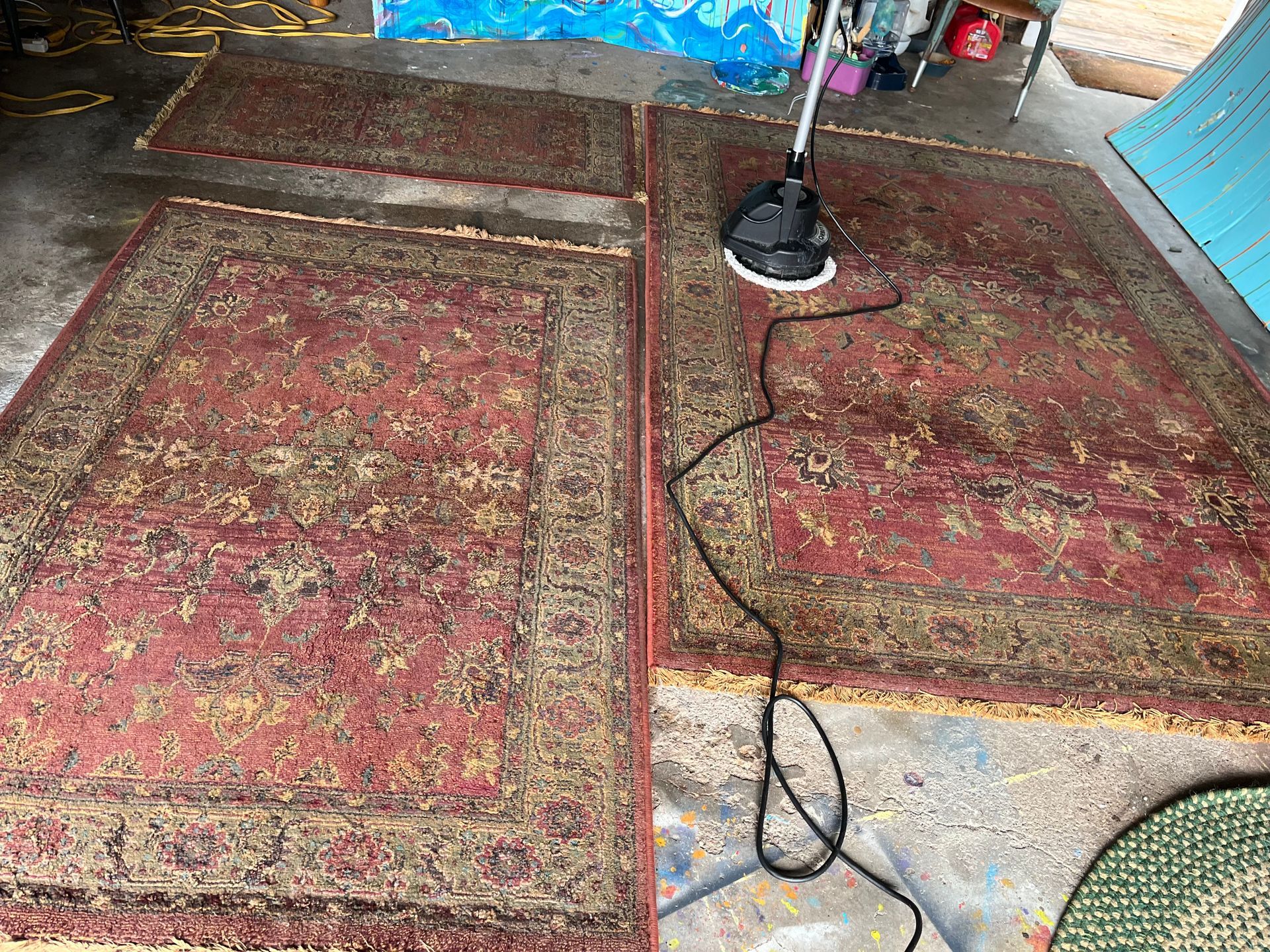 Two red patterned rugs on a floor with a microphone stand and cable between them