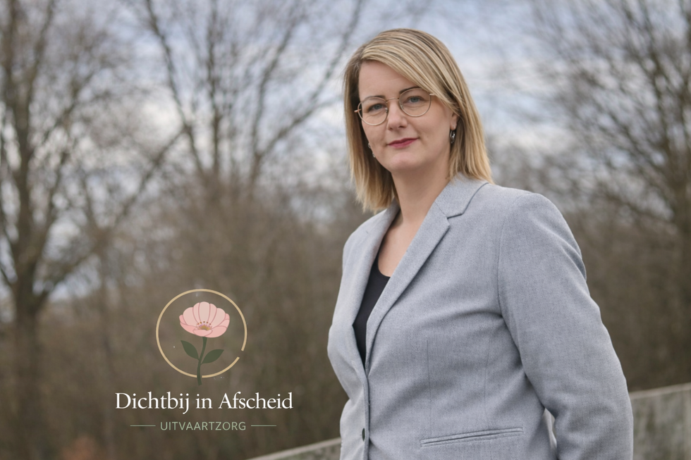 Woman in a gray blazer stands near greenery, logo