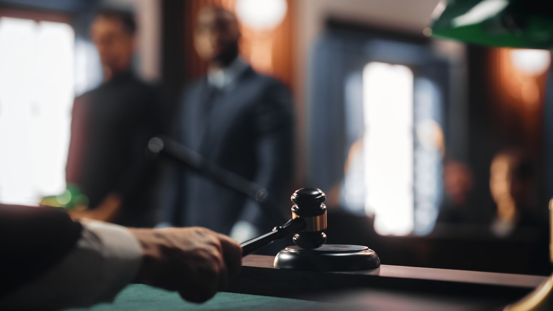 A man is holding a judge 's gavel in a courtroom.