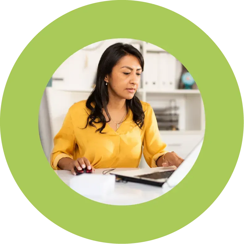 A concerned looking woman at a desk working on a laptop