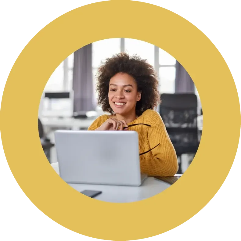 Happy, female office worker smiling in front of a laptop
