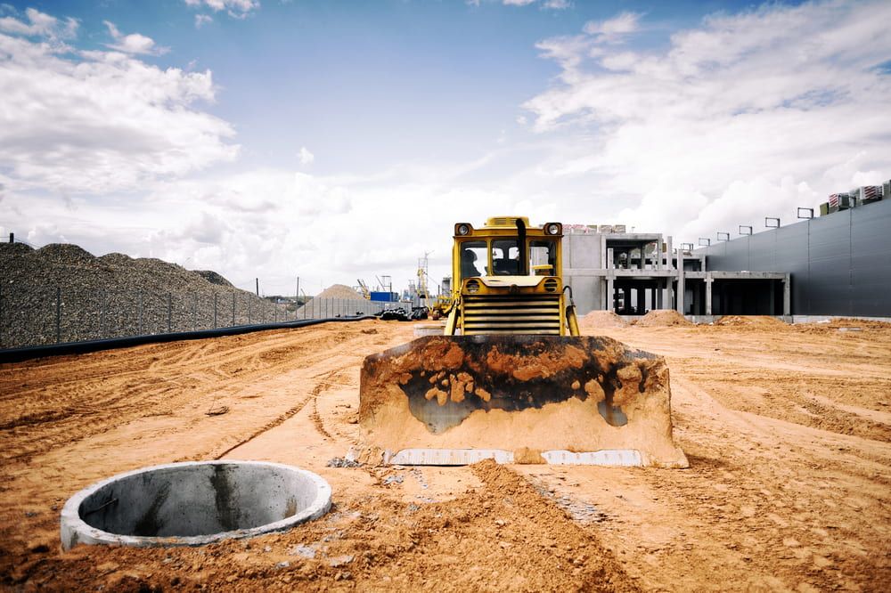 A Bulldozer is Moving Dirt on a Construction Site — Matt's Mini Machines in Palmwoods, QLD