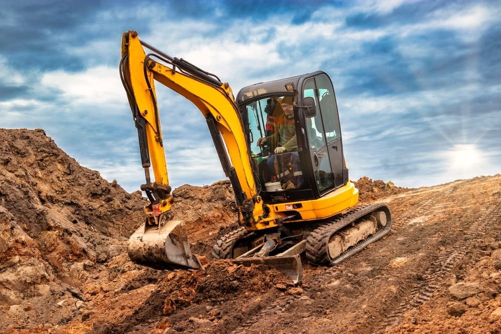 A Yellow Excavator is Moving Dirt on a Construction Site — Matt's Mini Machines in Palmwoods, QLD