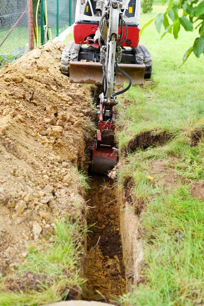 A Small Excavator is Digging a Trench in the Ground — Matt's Mini Machines in Yandina, QLD