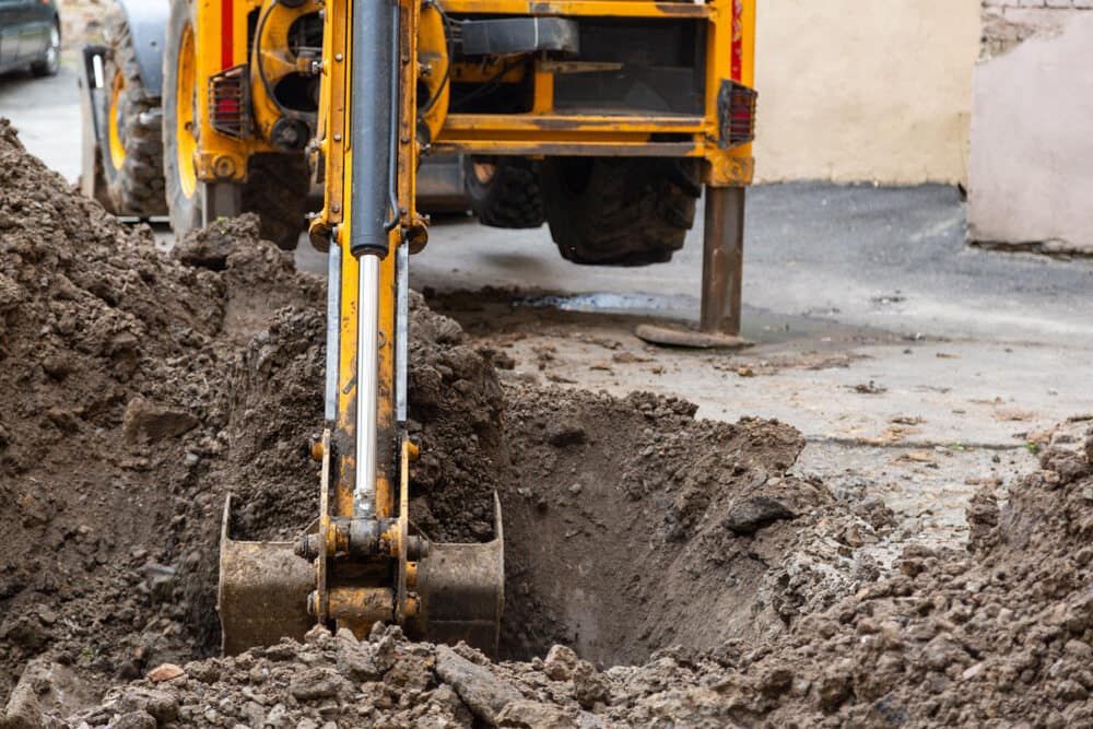 A Yellow Excavator is Digging a Hole in the Ground — Matt's Mini Machines in Rosemount, QLD