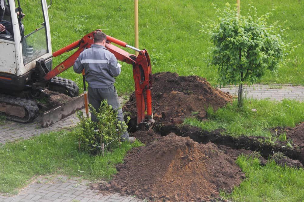 A Man is Using a Small Excavator to Dig a Hole in the Ground — Matt's Mini Machines in Bli Bli, QLD
