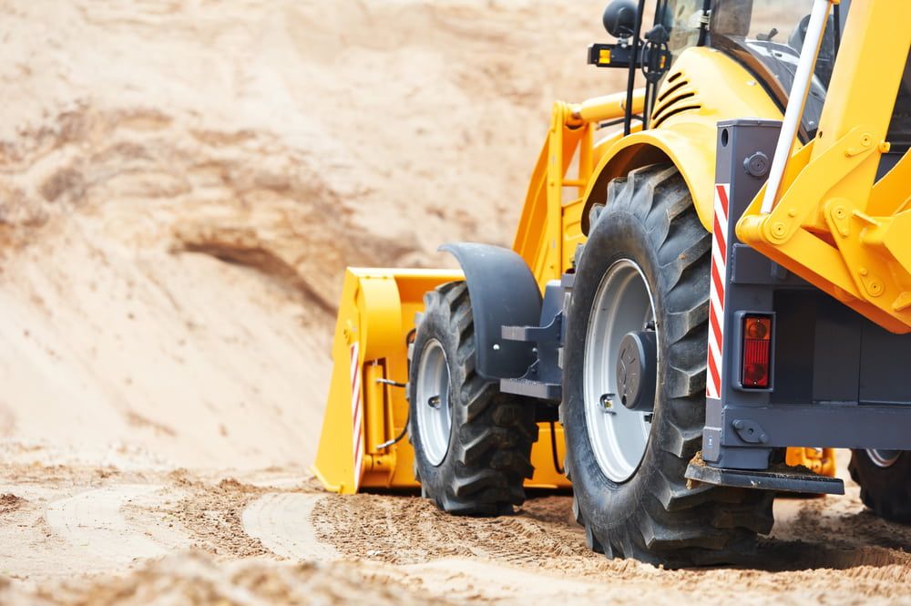 A Yellow Tractor is Driving Through a Dirt Field — Matt's Mini Machines in Yandina, QLD