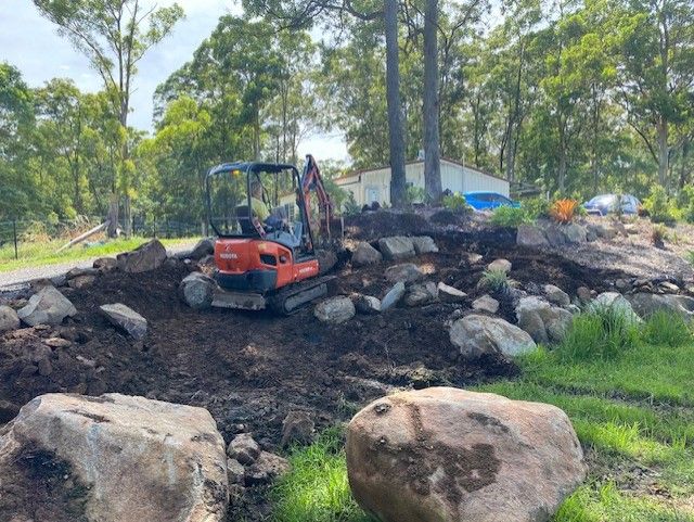 A Bulldozer is Moving Dirt in Front of a House — Matt's Mini Machines in Bli Bli, QLD