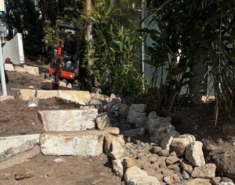 A Yellow Tractor is Driving Through a Dirt Field — Matt's Mini Machines in Bli Bli, QLD