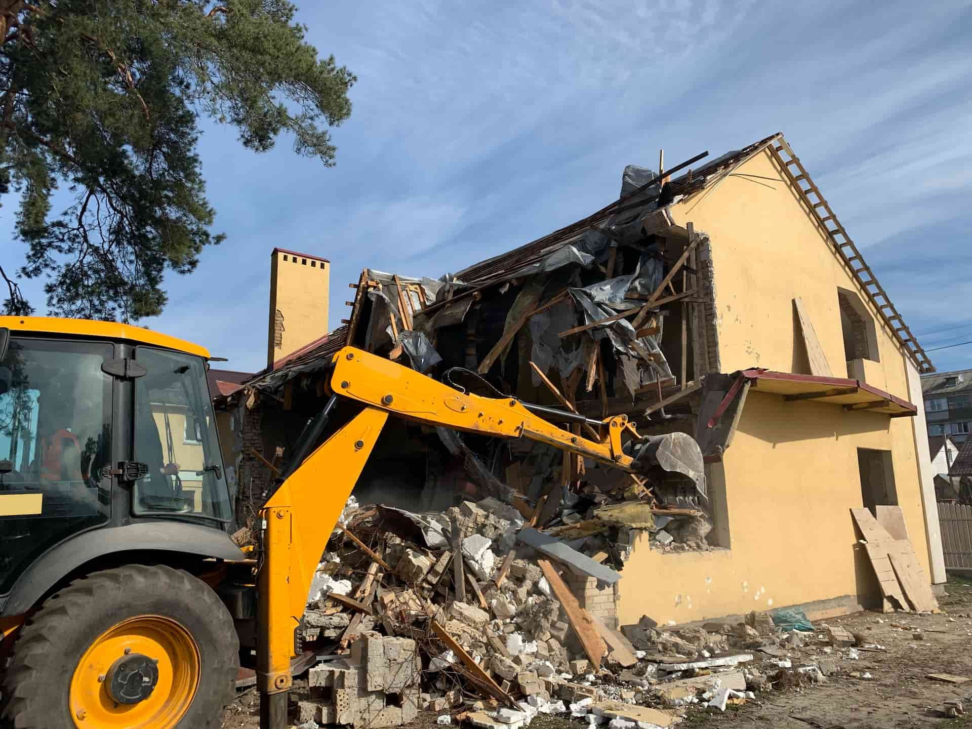 A Yellow Bulldozer is Demolishing a Yellow House — Matt's Mini Machines in Bli Bli, QLD