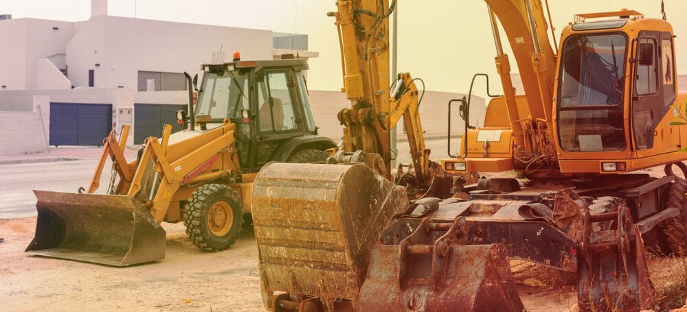 Two Yellow Excavators Are Parked Next to Each Other on a Construction Site — Matt's Mini Machines in Rosemount, QLD