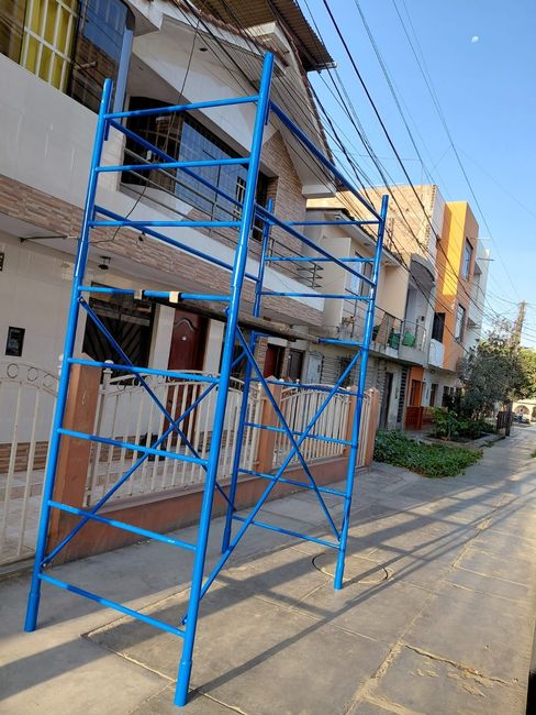 Andamios metálicos azules en una calle junto a edificios residenciales en construcción.