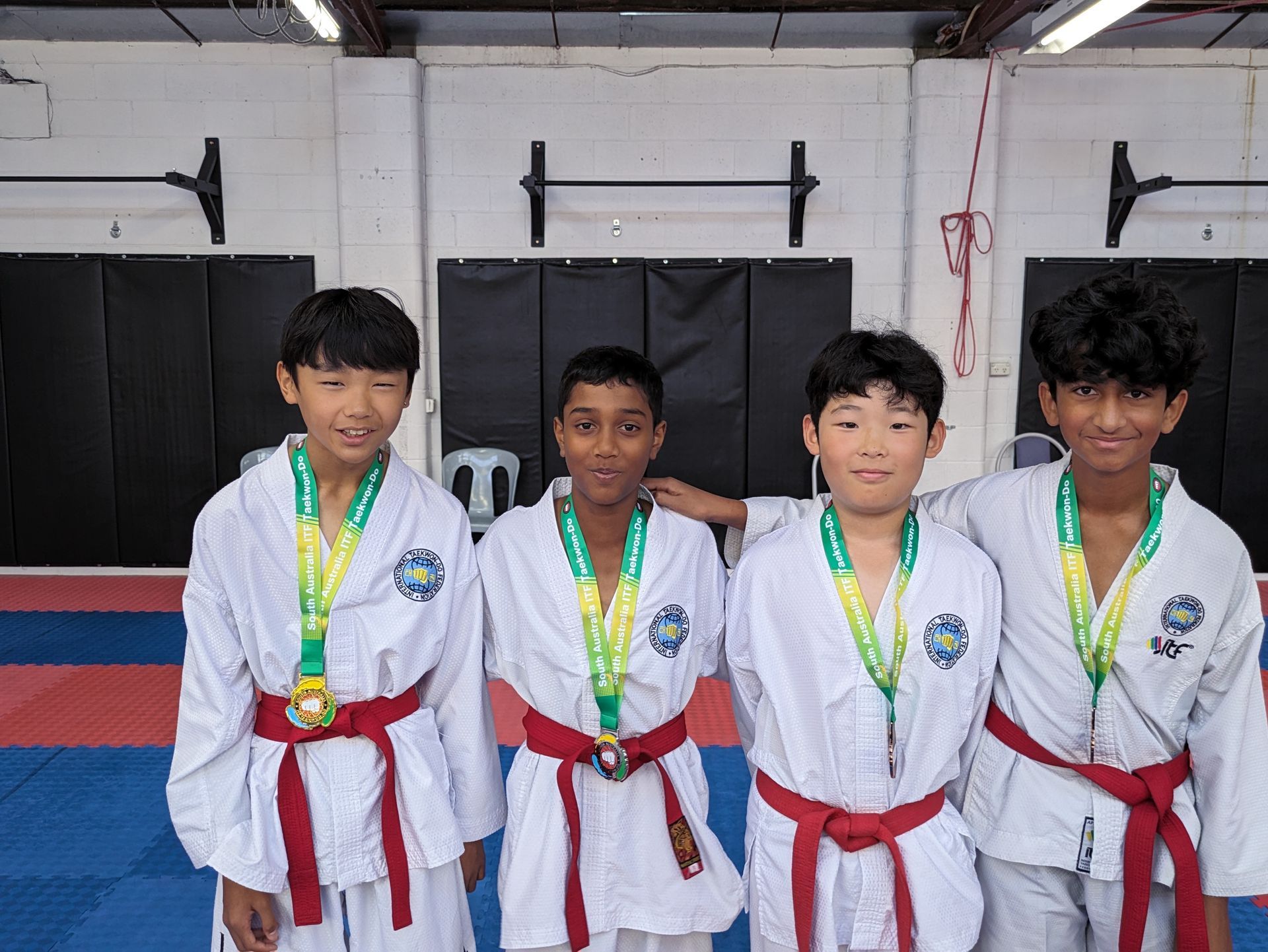 Students in white karate uniforms line up with red belt.