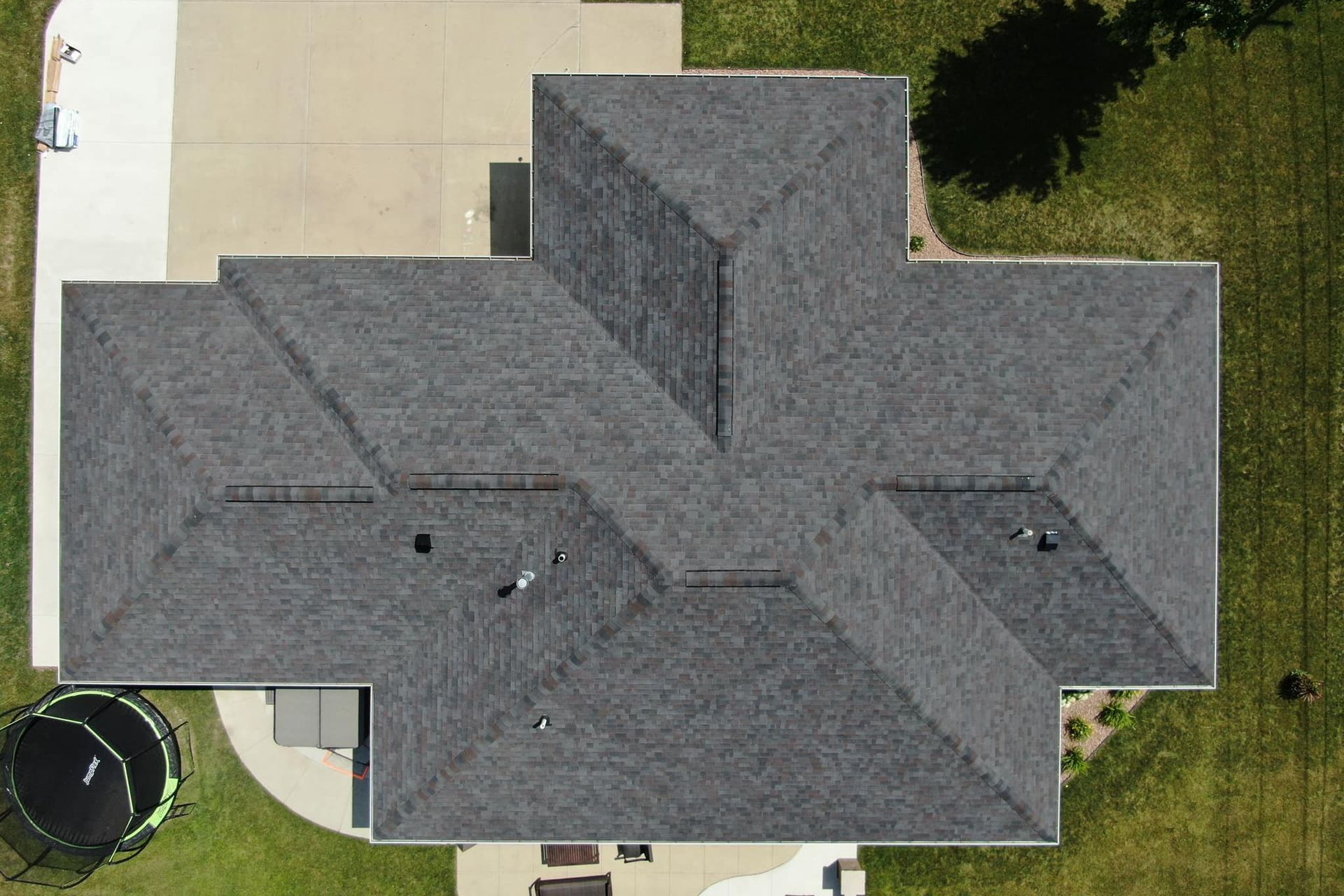 An aerial view of the roof of a house with a trampoline in the backyard.