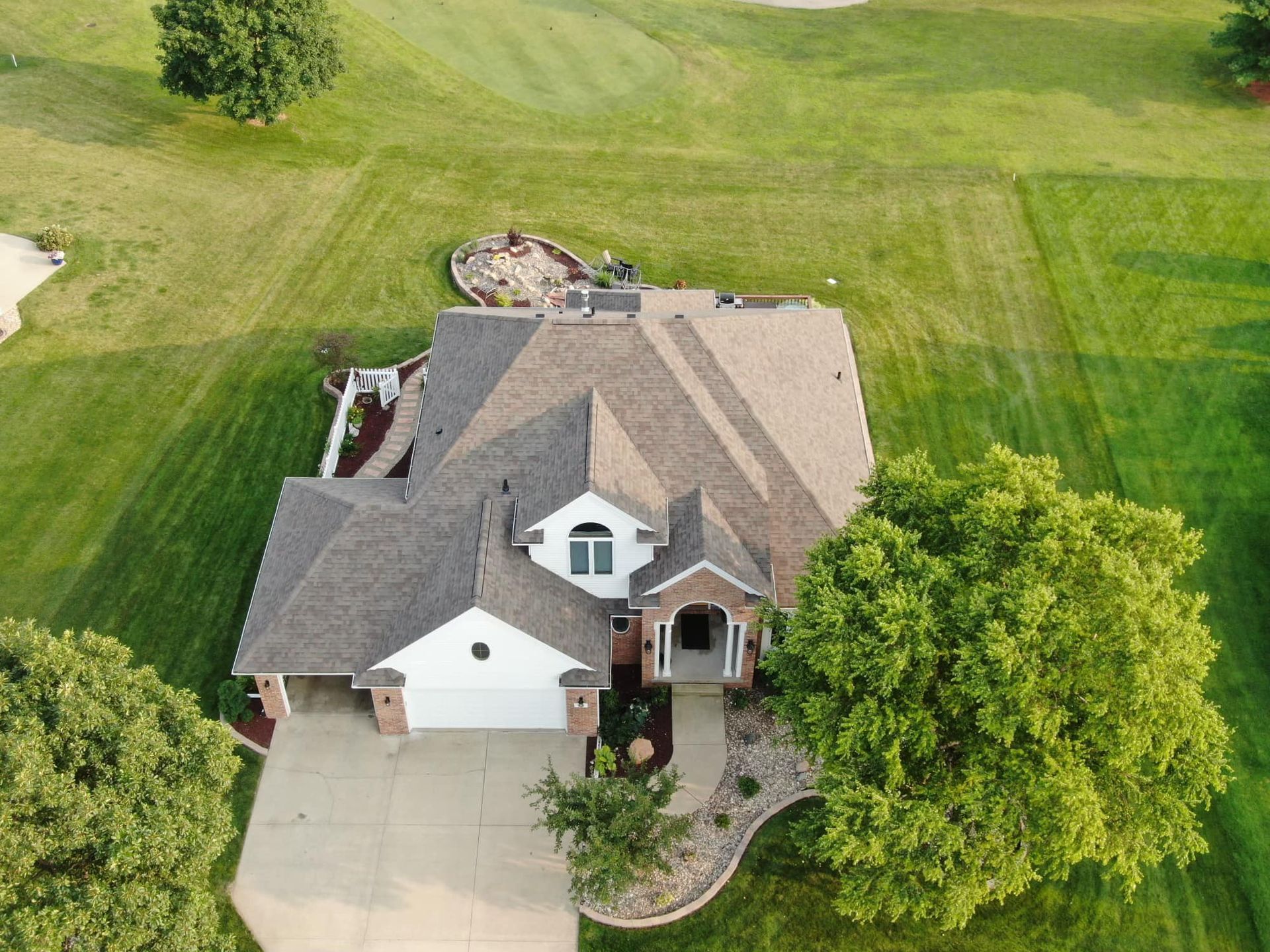 An aerial view of a house with a golf course in the background