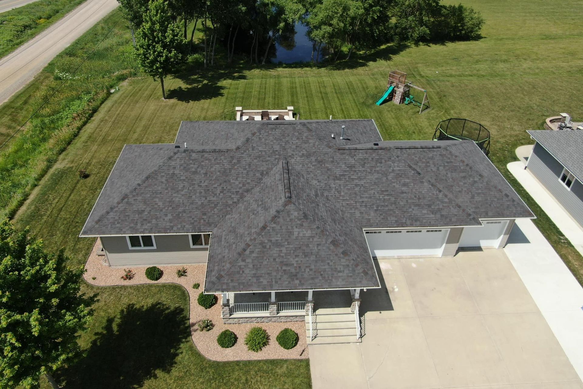 An aerial view of a house with a gray roof and a driveway.