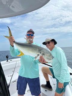 Two anglers on a boat holding a large silver fish at sea