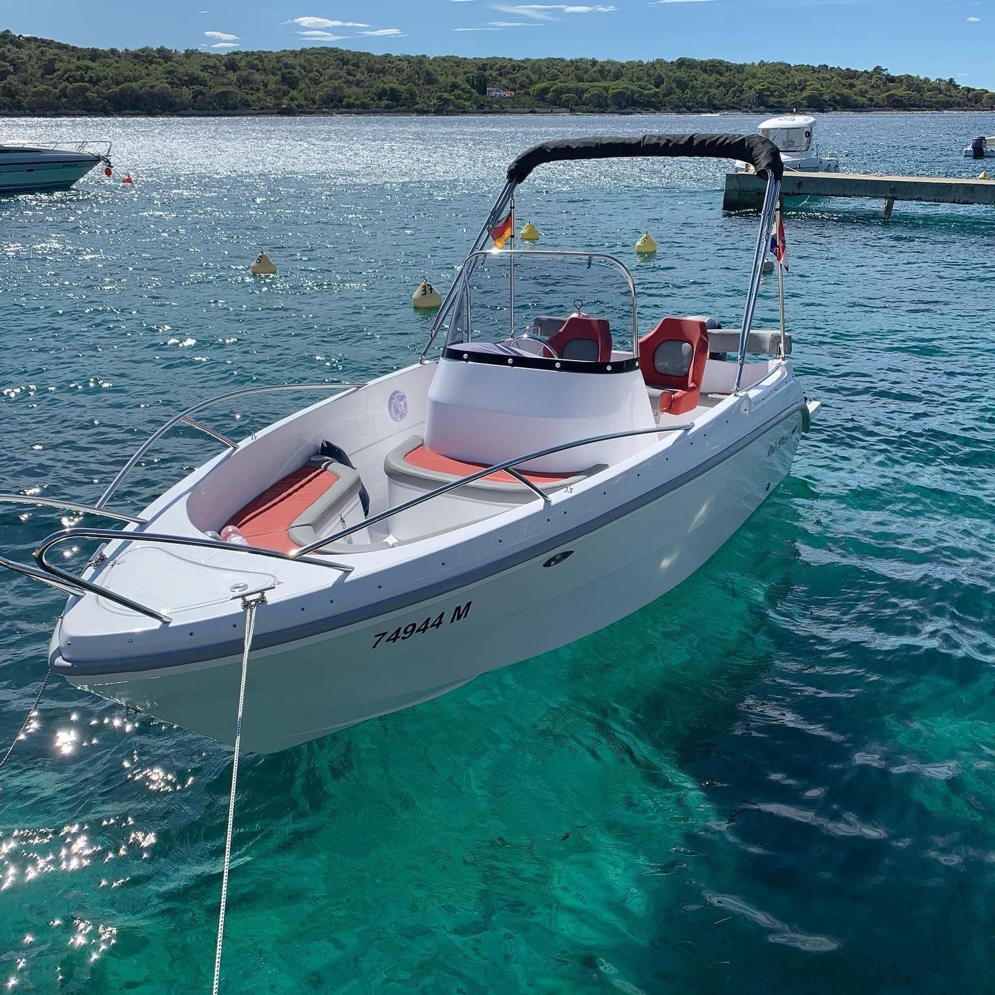 Een witte boot met een rode stoel is vastgebonden aan een steiger in het water