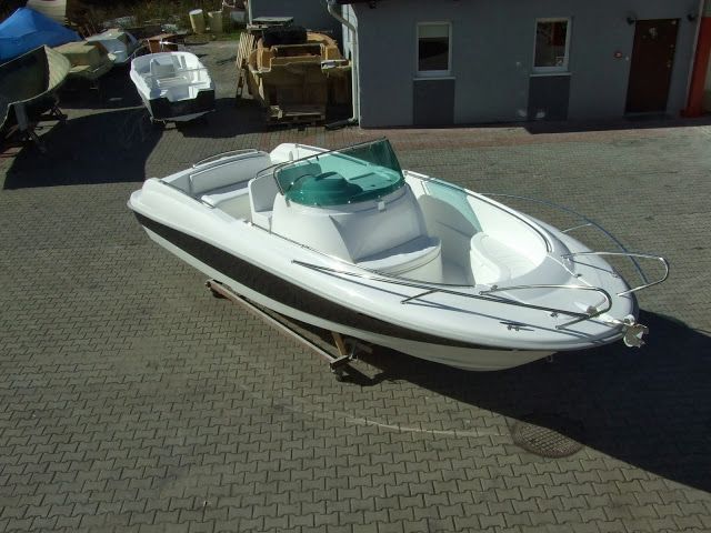 Een witte boot ligt geparkeerd op een bakstenen stoep voor een gebouw