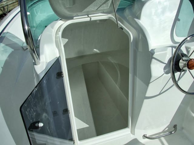 Een witte boot met een stuurwiel en een open kofferbak