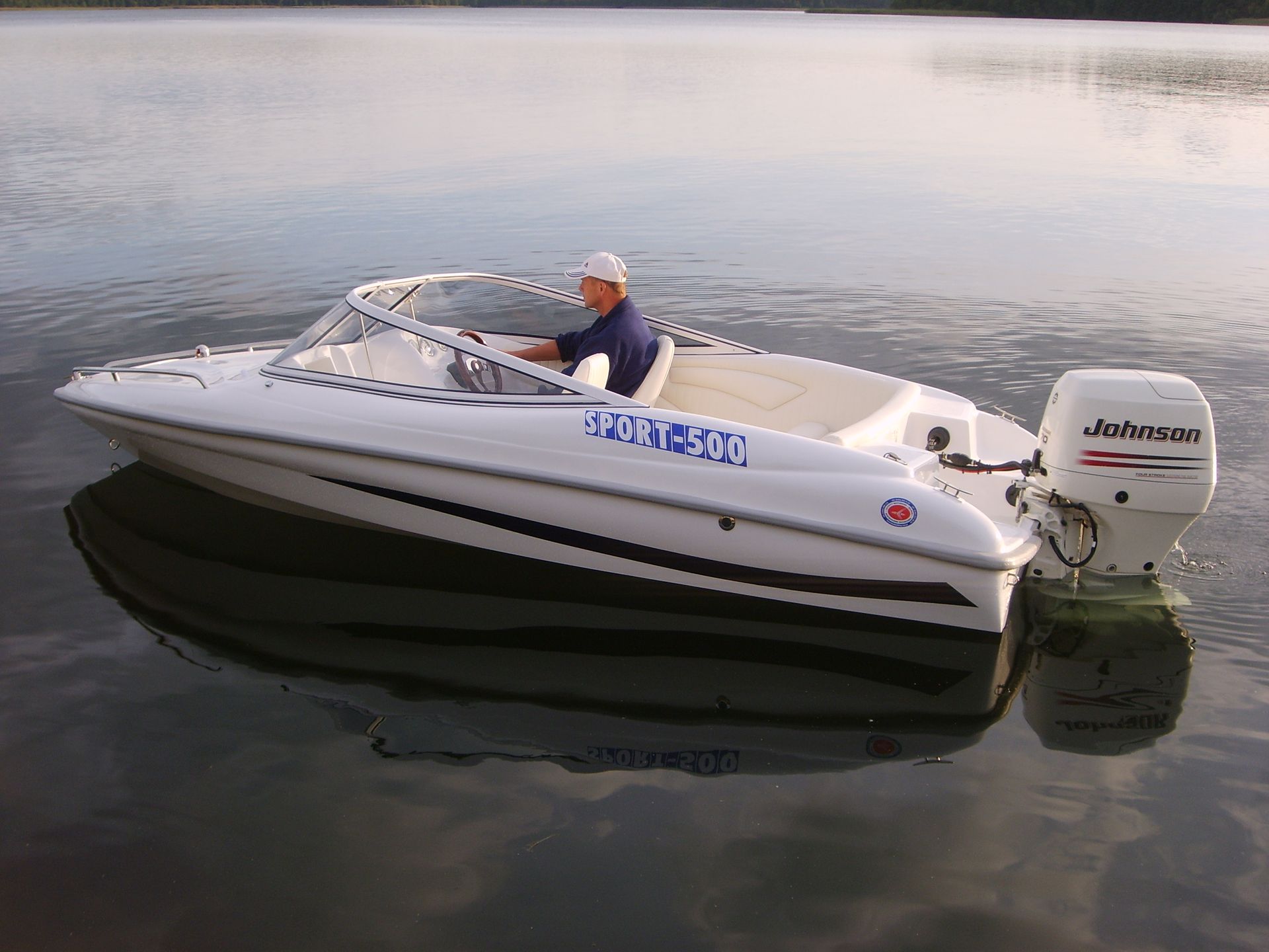 Een man bestuurt een witte boot op een meer.