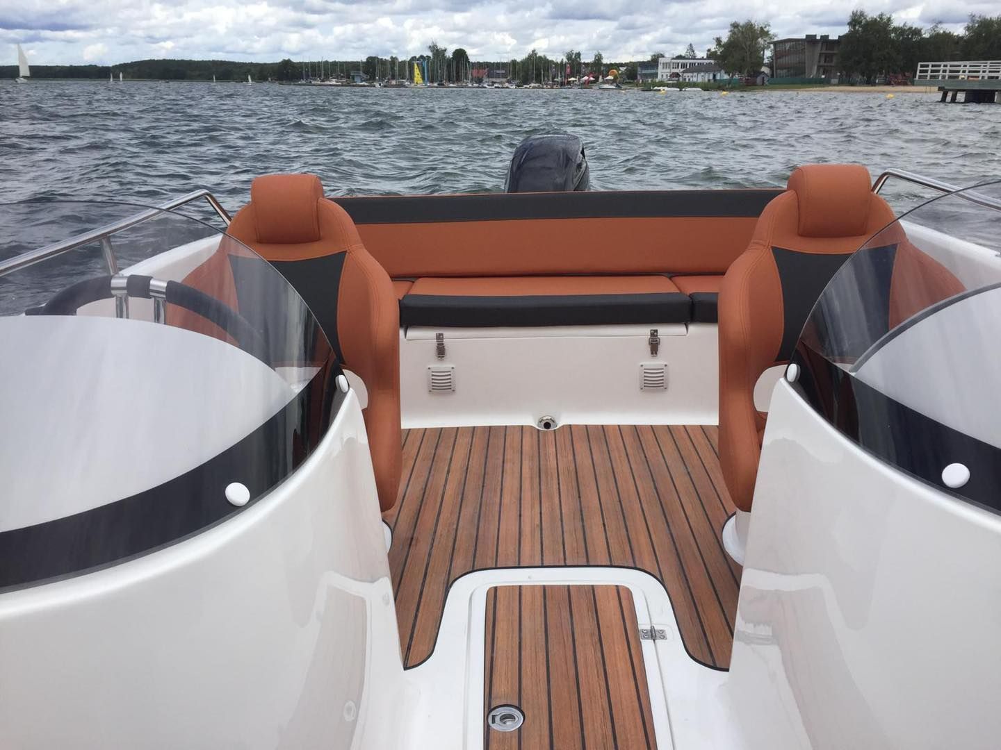 Een boot met een houten dek drijft op een meer.