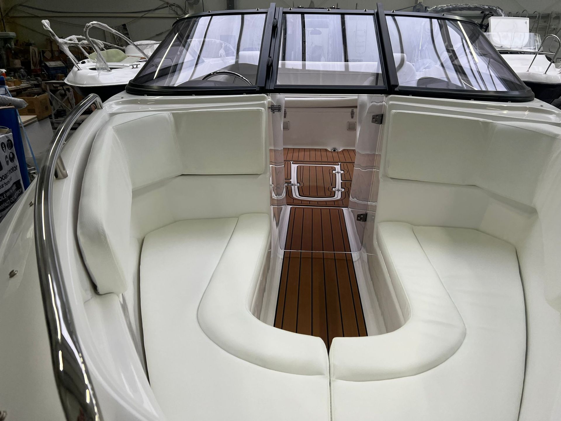 De binnenkant van een boot met witte stoelen en een houten dek.