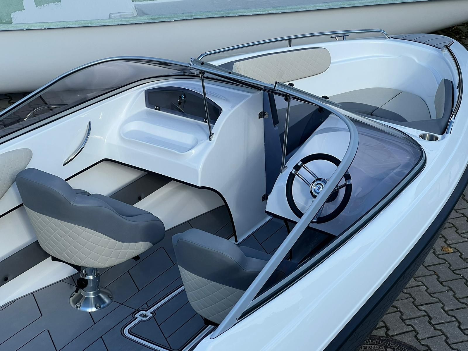 Een witte boot met grijze stoelen en een stuurwiel