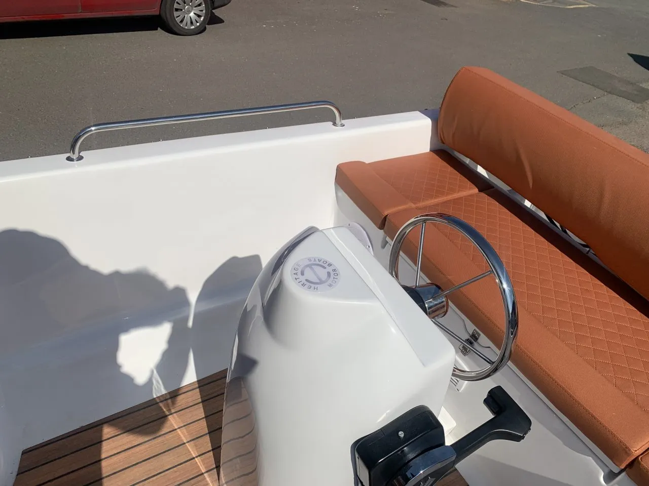 Een witte boot met bruine stoelen en een stuurwiel