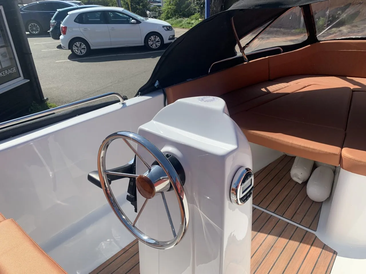 Een boot met een stuurwiel en een auto geparkeerd op de achtergrond