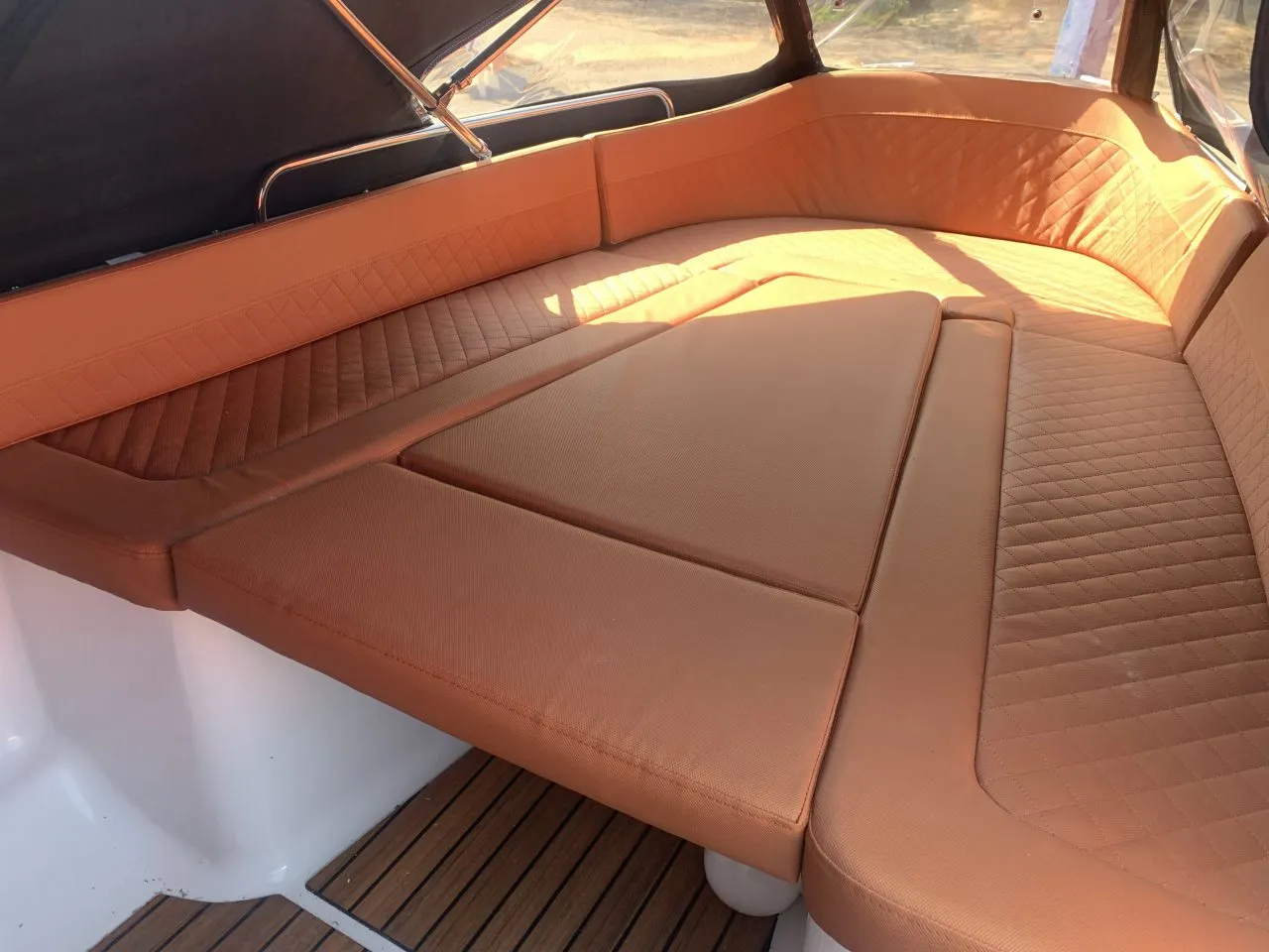 De binnenkant van een boot met bruine kussens en een houten vloer.