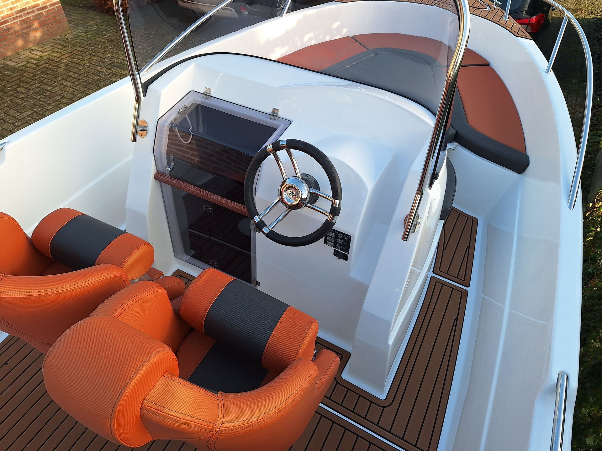 Een witte boot met oranje stoelen en een stuurwiel