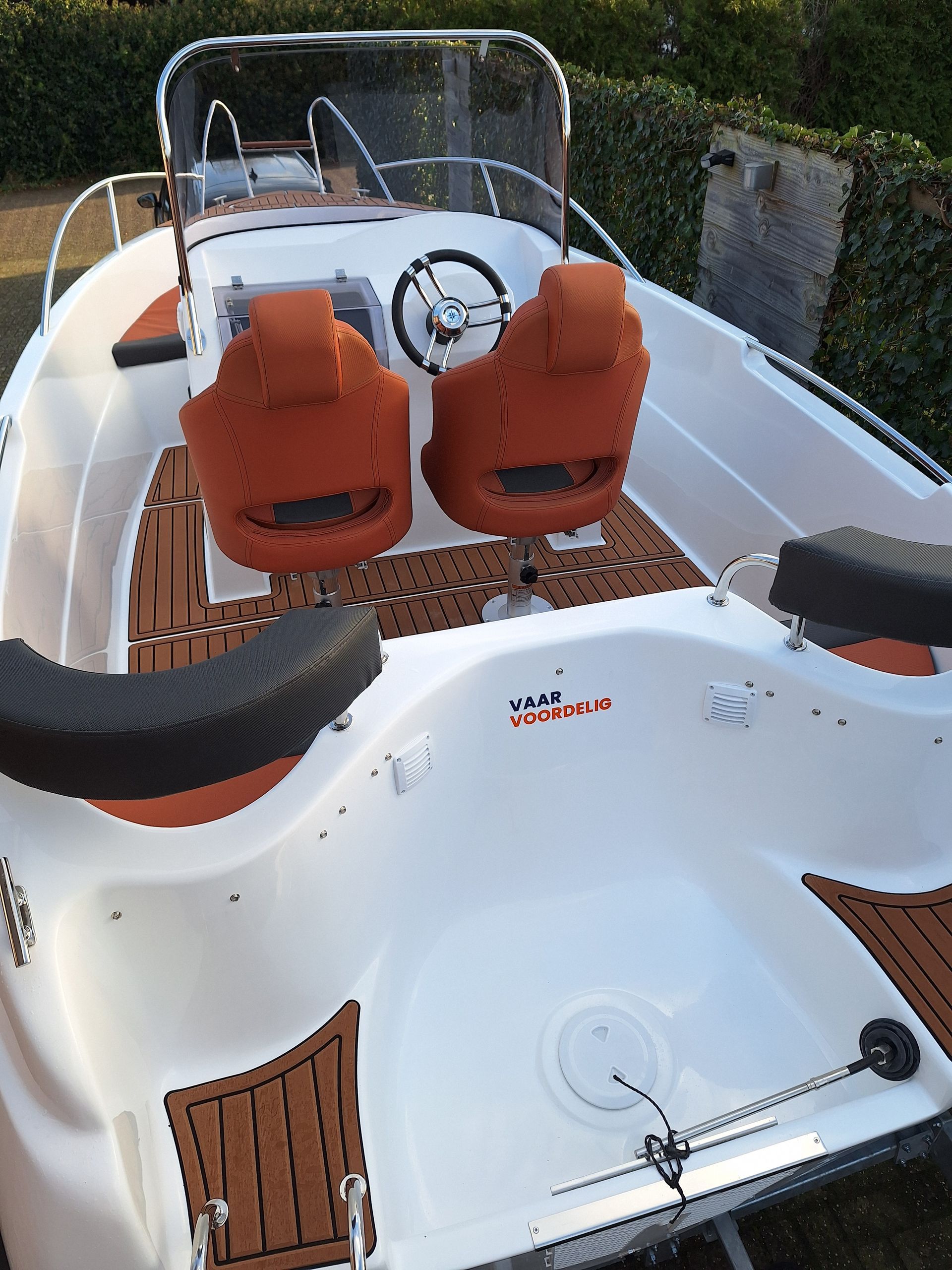 Een witte boot met oranje stoelen en een stuurwiel