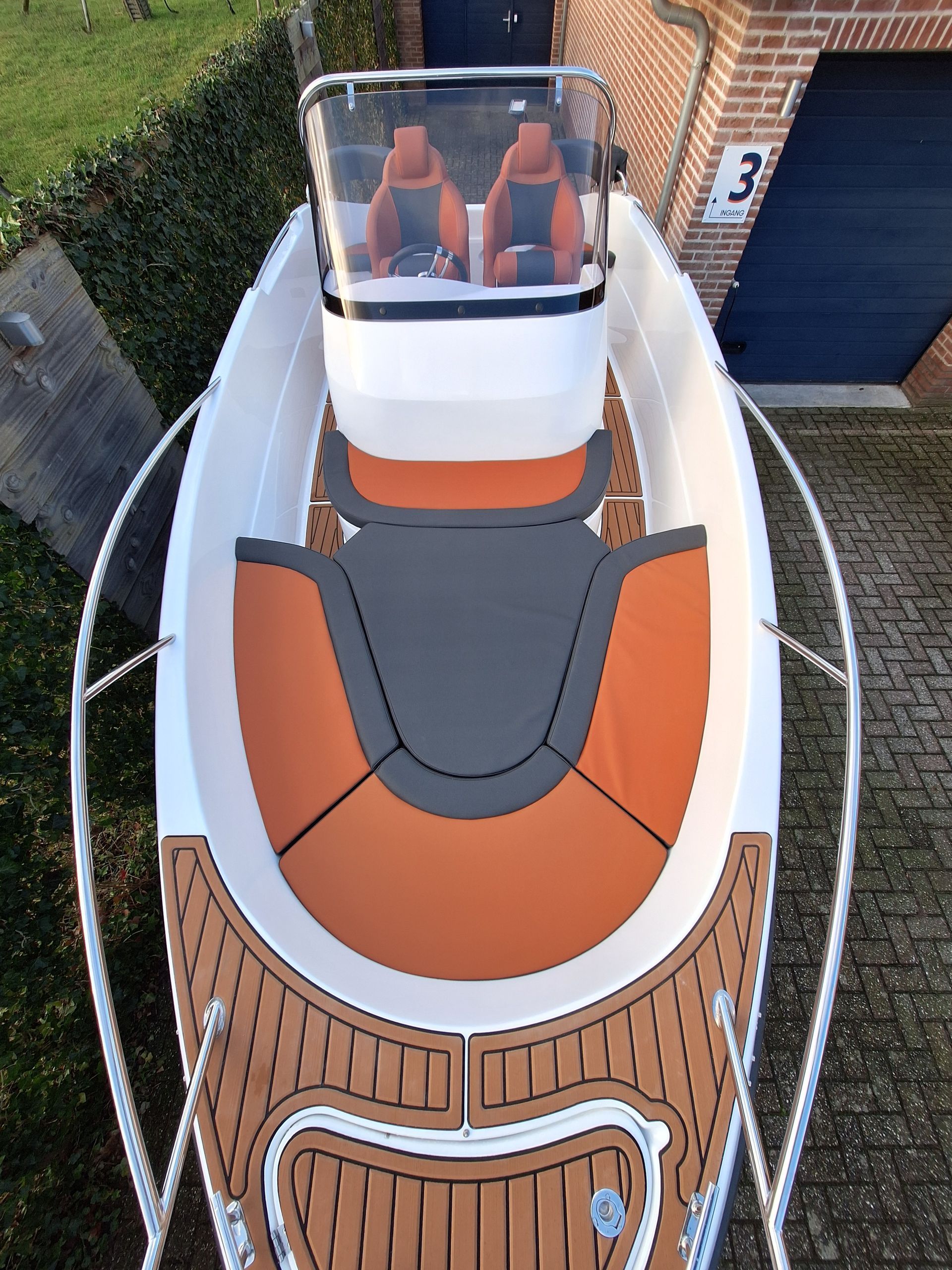 Een wit-oranje boot ligt geparkeerd voor een bakstenen gebouw