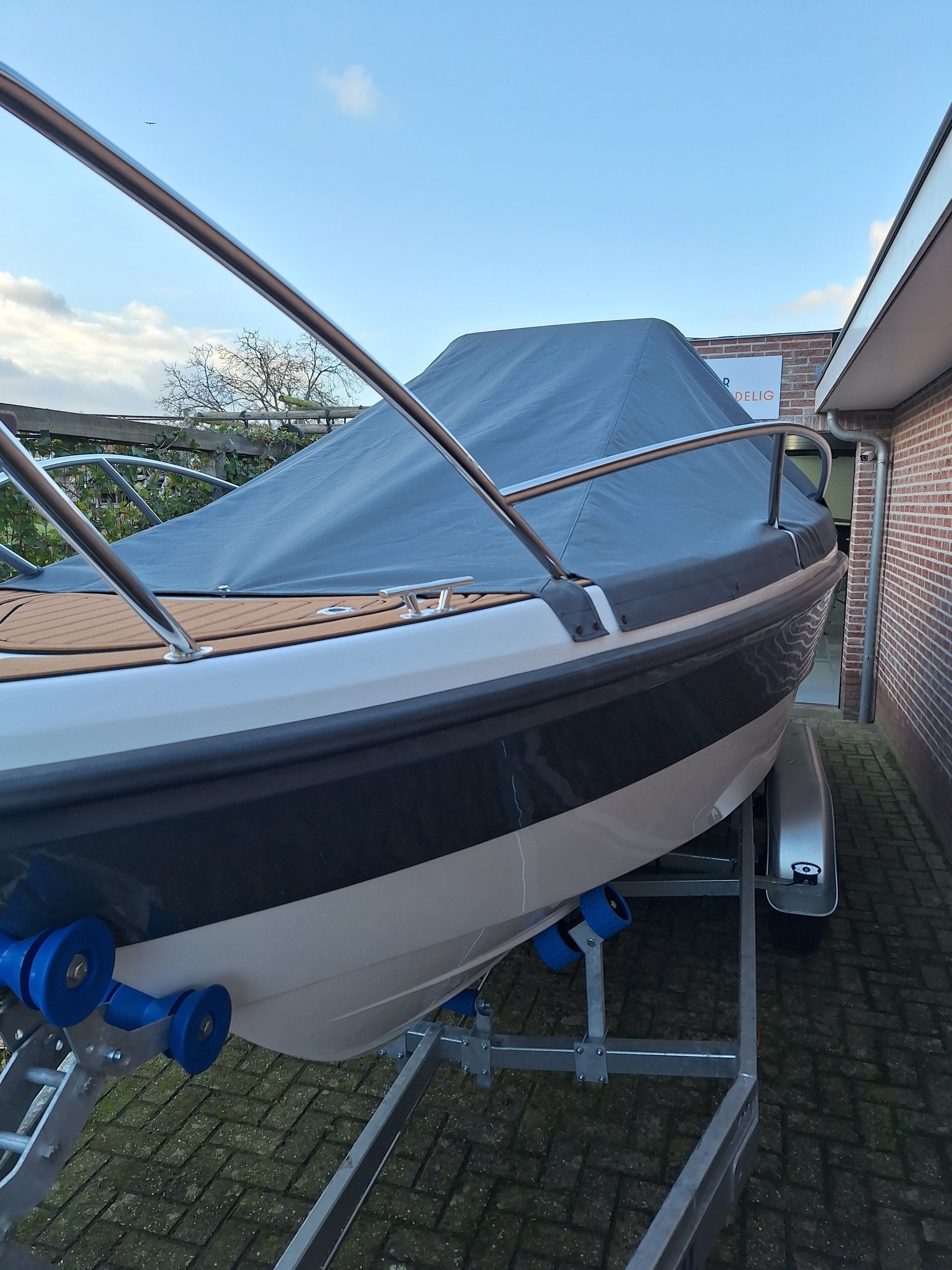 Een boot met een dekzeil erop ligt op een trailer.