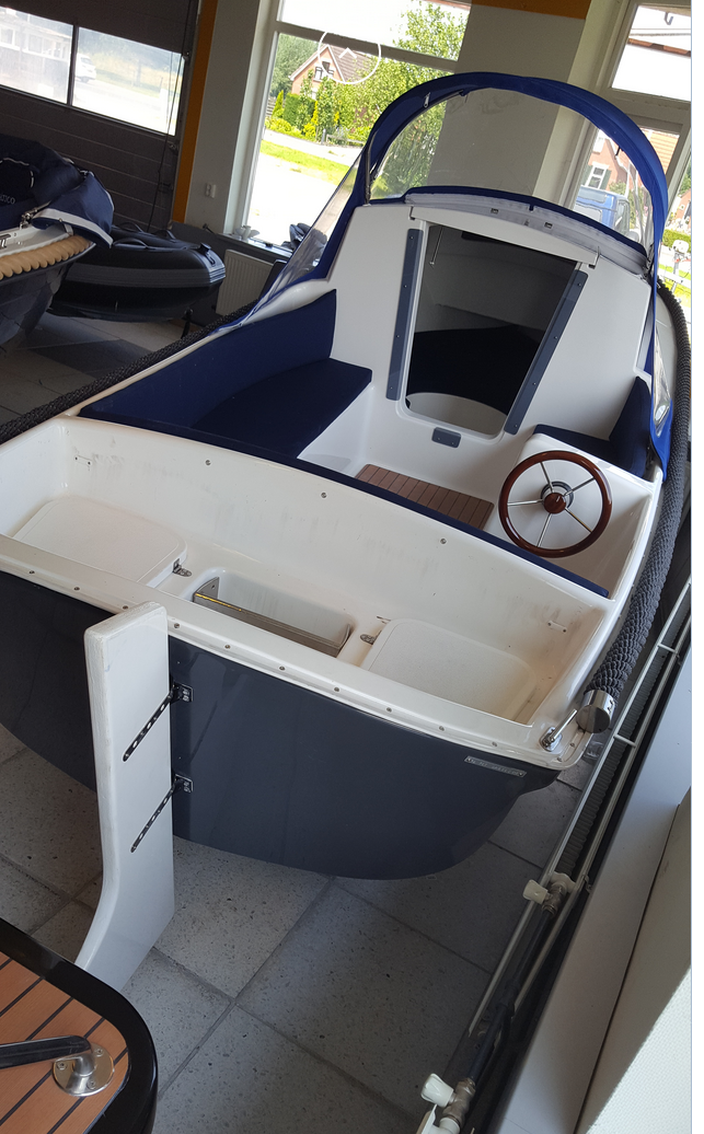 Een kleine blauw-witte boot met een stuurwiel