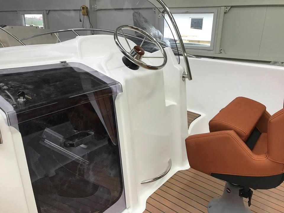Een witte boot met een bruine stoel en stuurwiel
