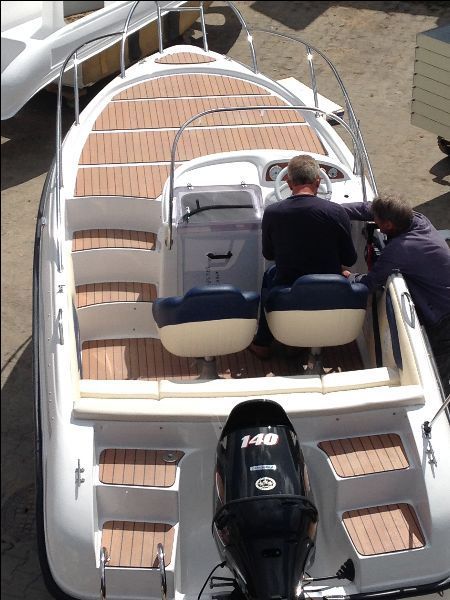 Een man zit aan het stuur van een boot met het nummer 140 op de achterkant
