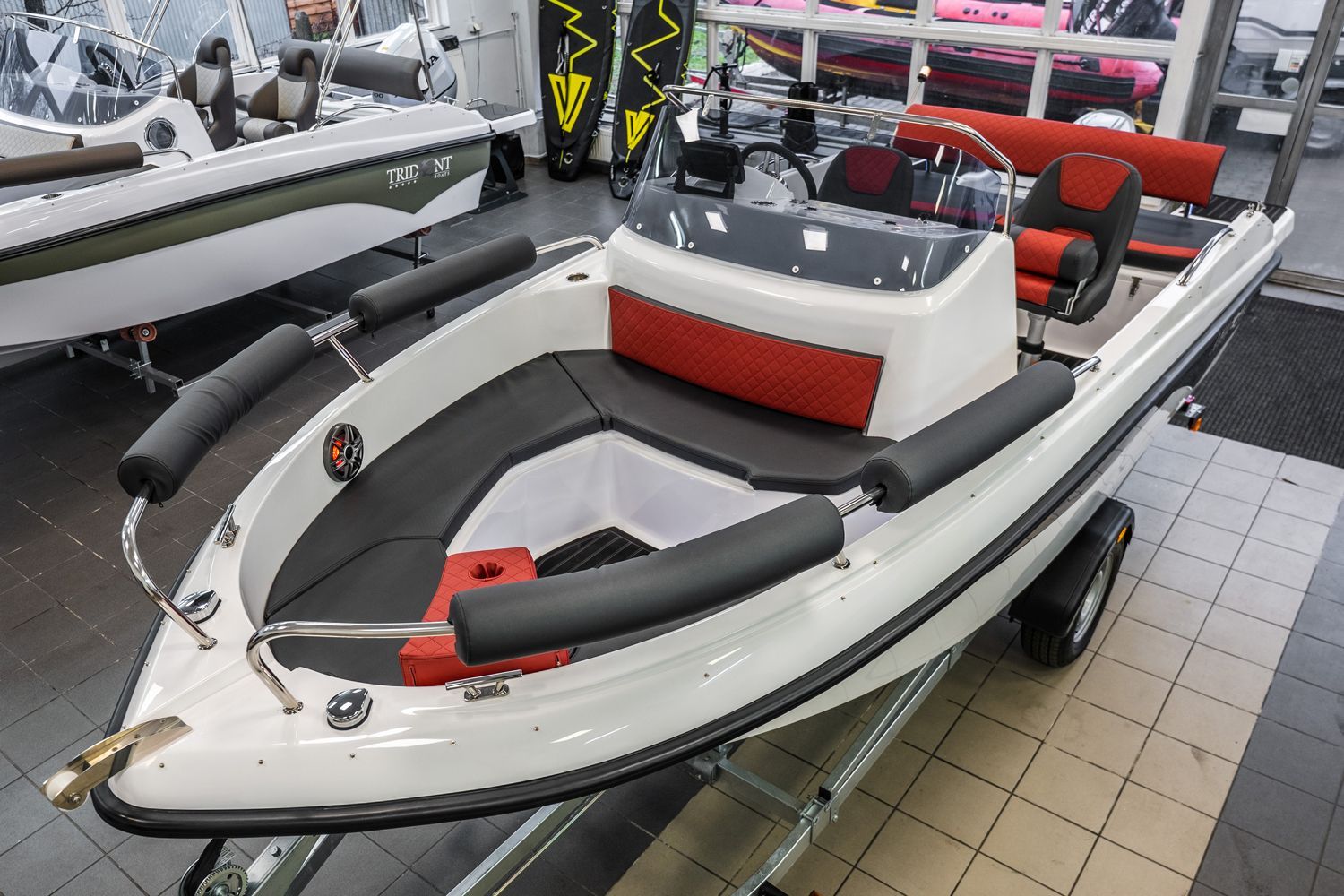 Een kleine boot staat op een trailer in een showroom.