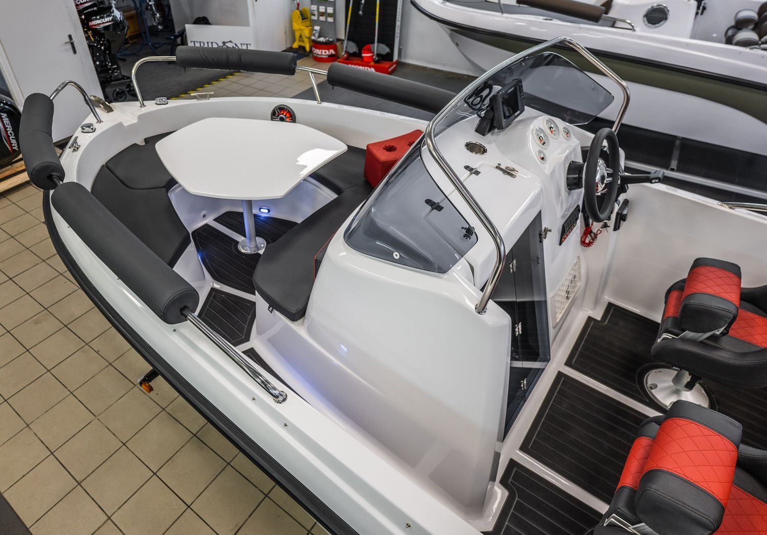 Een witte boot met een tafel en stoelen staat geparkeerd in een garage.