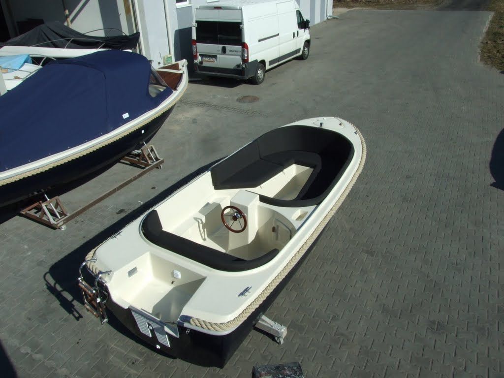 Een witte bestelwagen staat geparkeerd naast een kleine boot