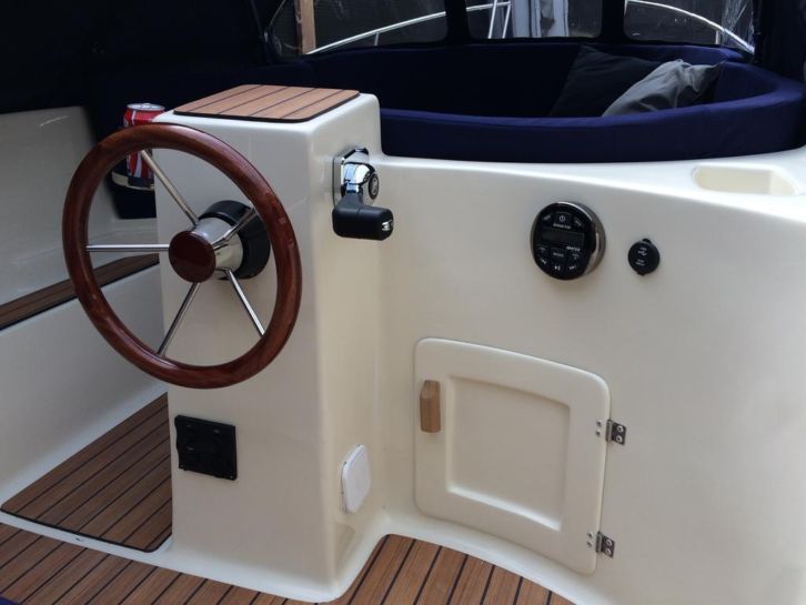 Een witte boot met een houten stuurwiel
