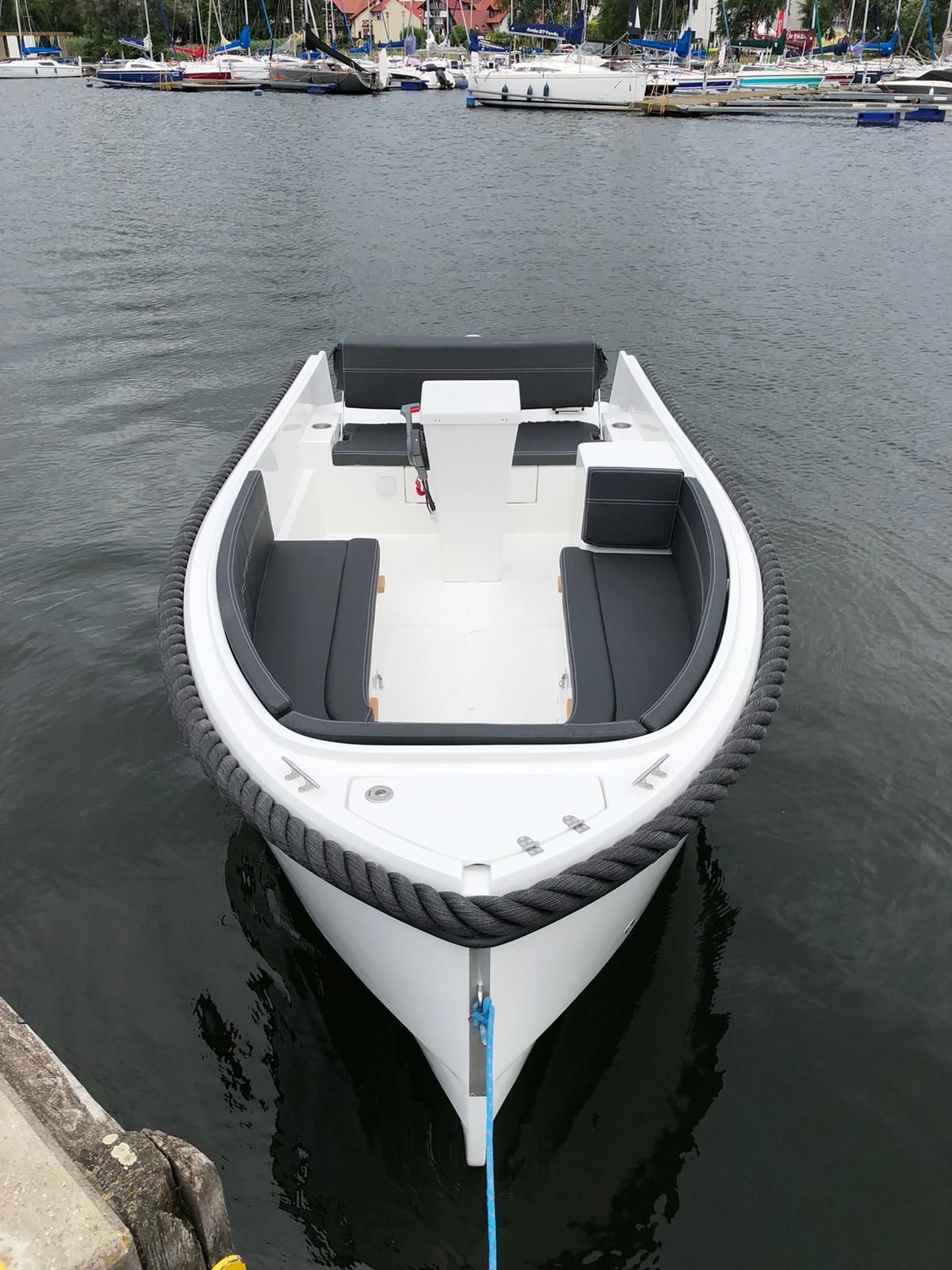 Een witte boot ligt vastgebonden aan een steiger in het water.