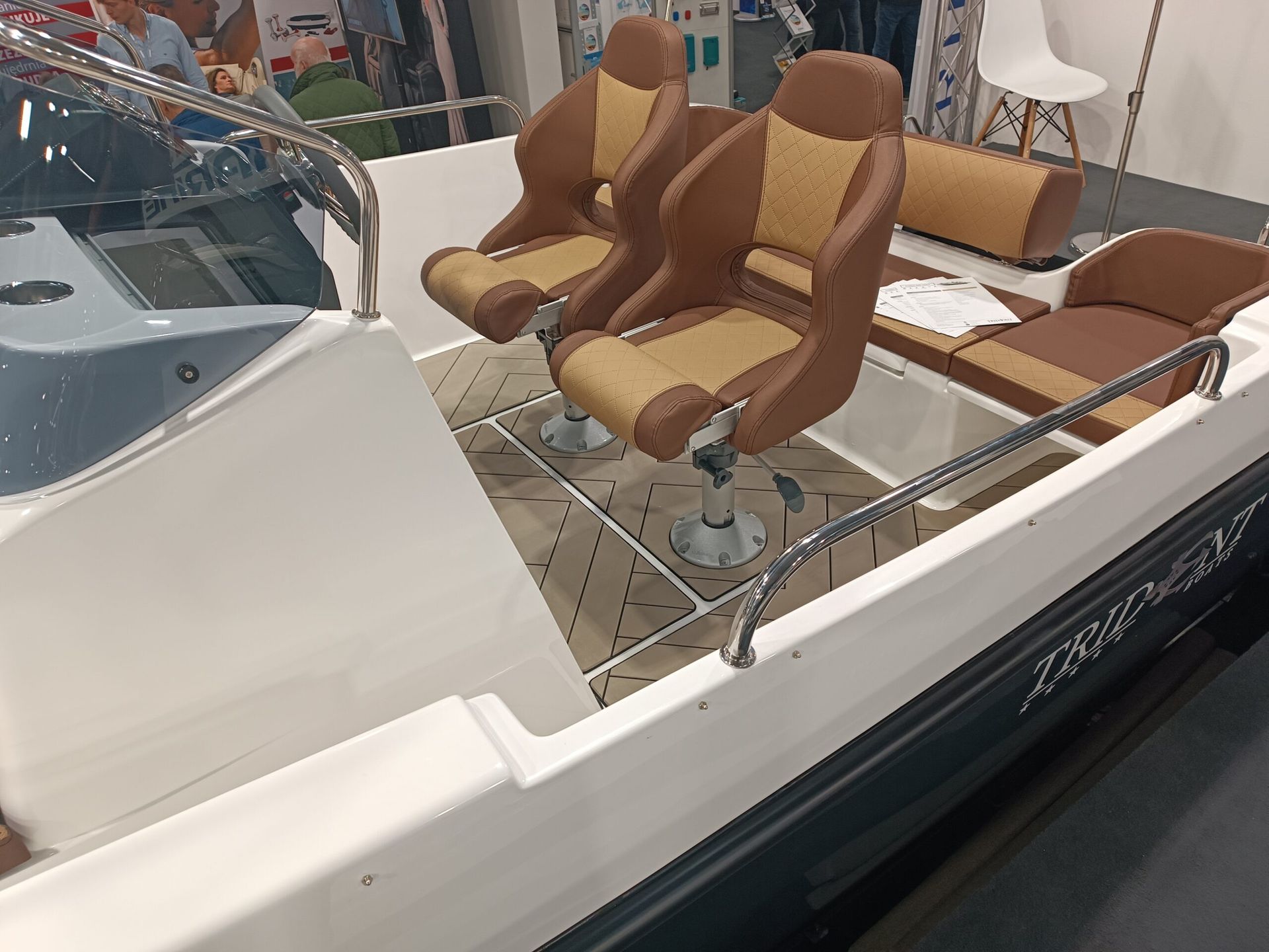 Een witte boot met bruine stoelen erop staat tentoongesteld op een botenbeurs.