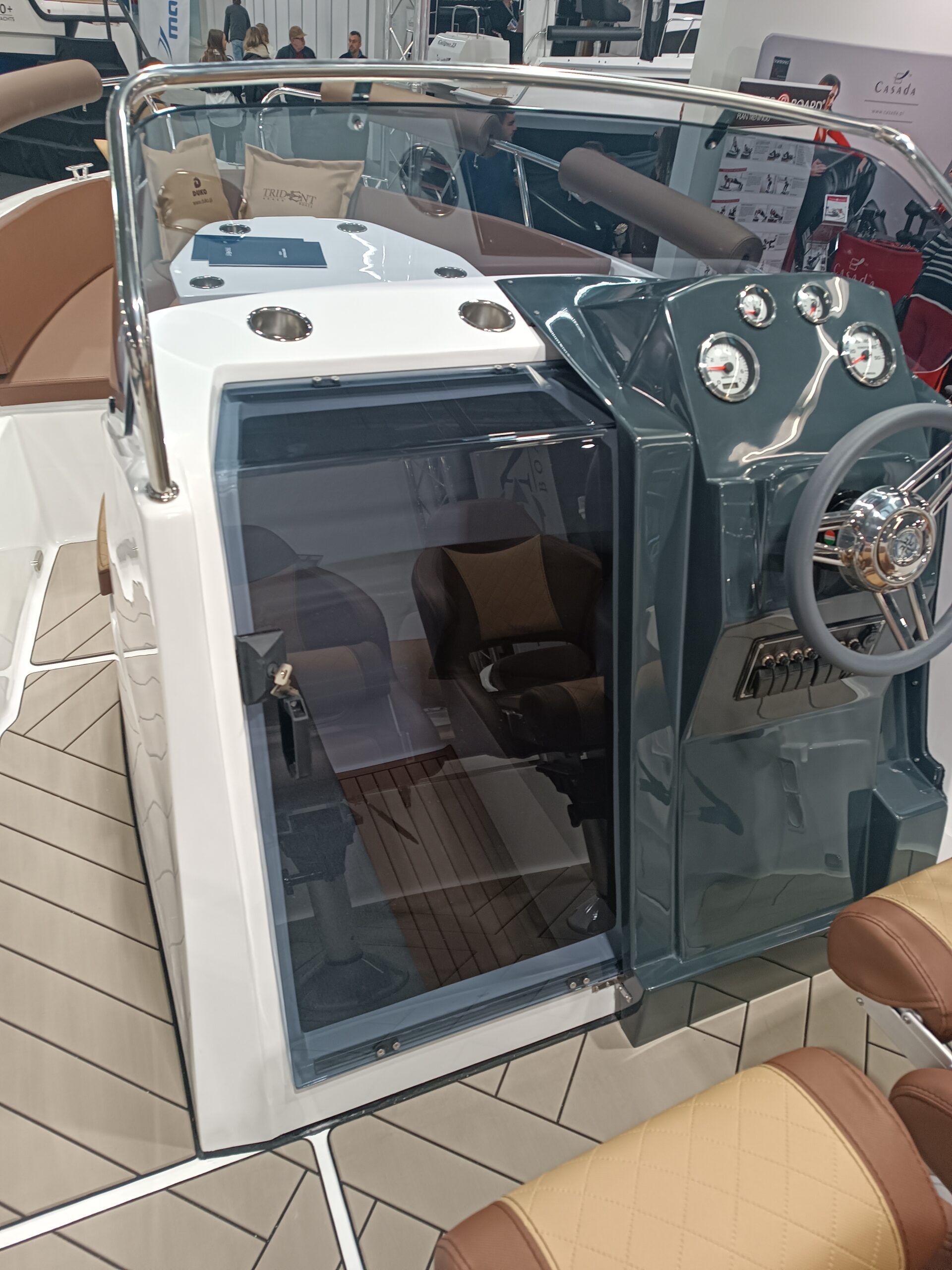 Een boot met een stuurwiel en een deur ligt op een steiger.