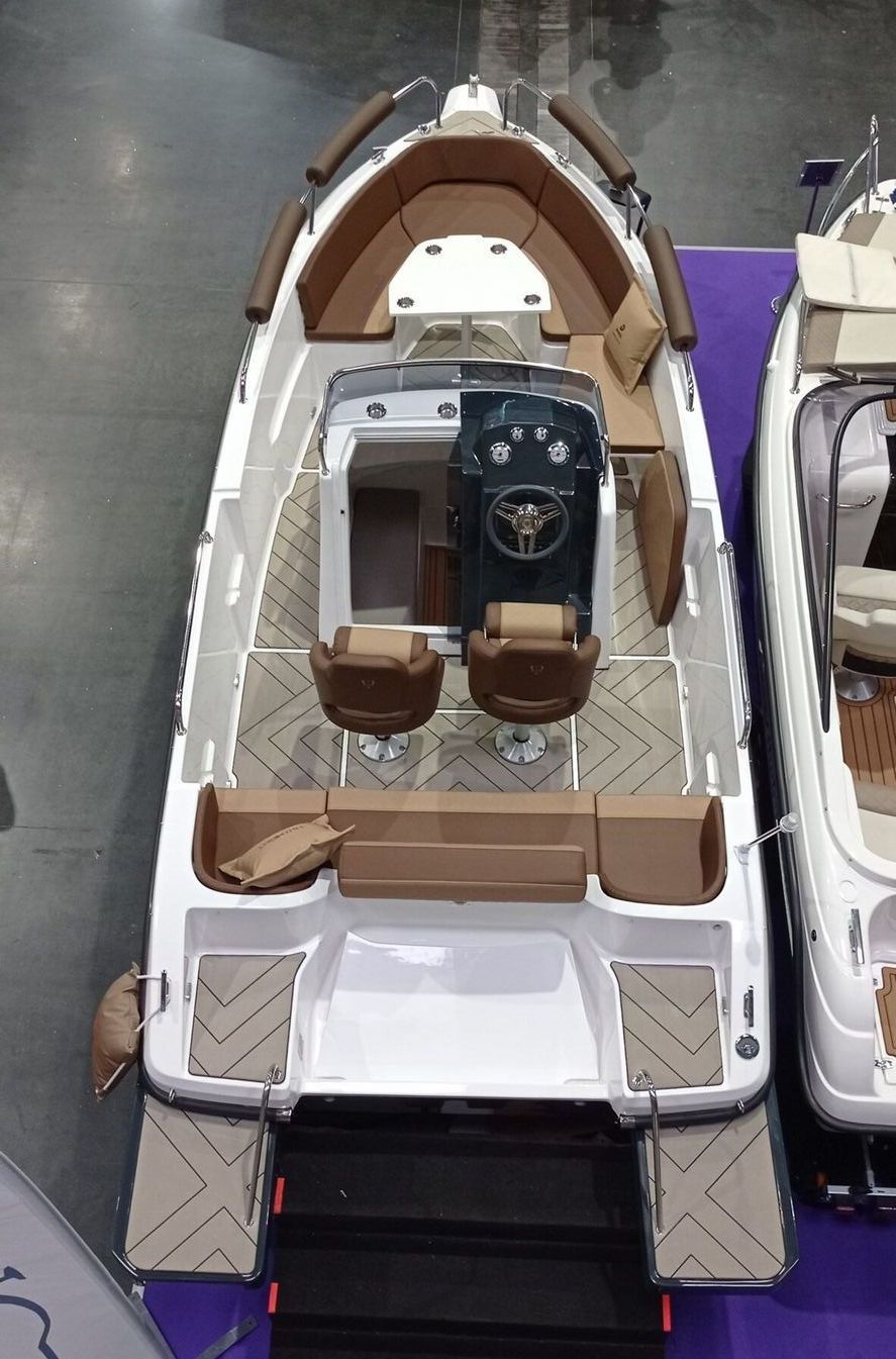 Een witte boot met bruine stoelen en een stuurwiel