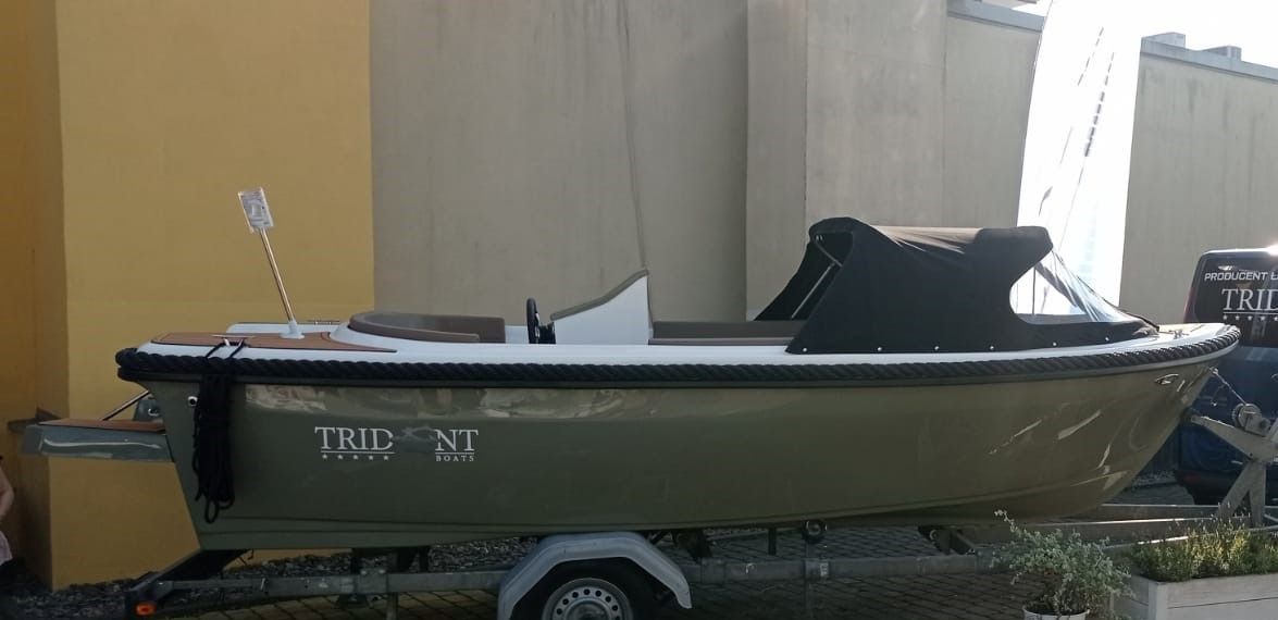 Een kleine boot staat op een trailer voor een gebouw geparkeerd.