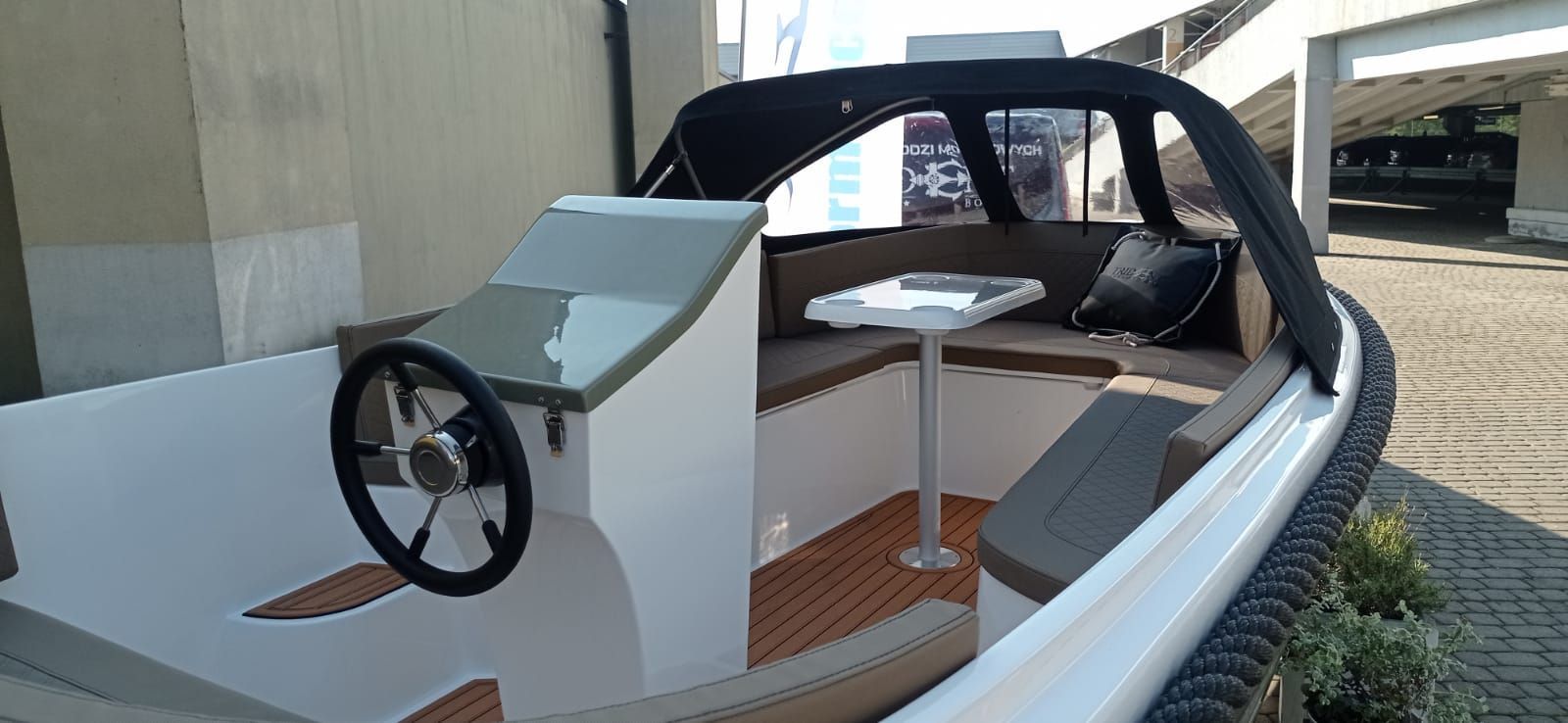 Een kleine witte boot met een tafel en stuurwiel